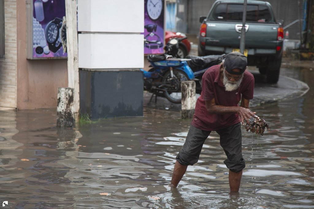 Man standing in a flooded street during the rainy season in Paramaribo, Suriname