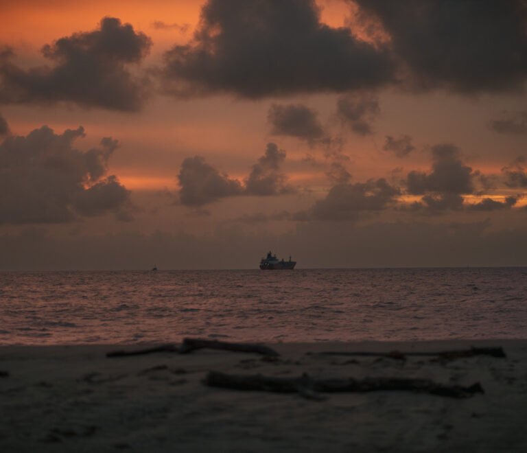 Cargo ship offshore at sunset with dramatic clouds over the sea in Suriname