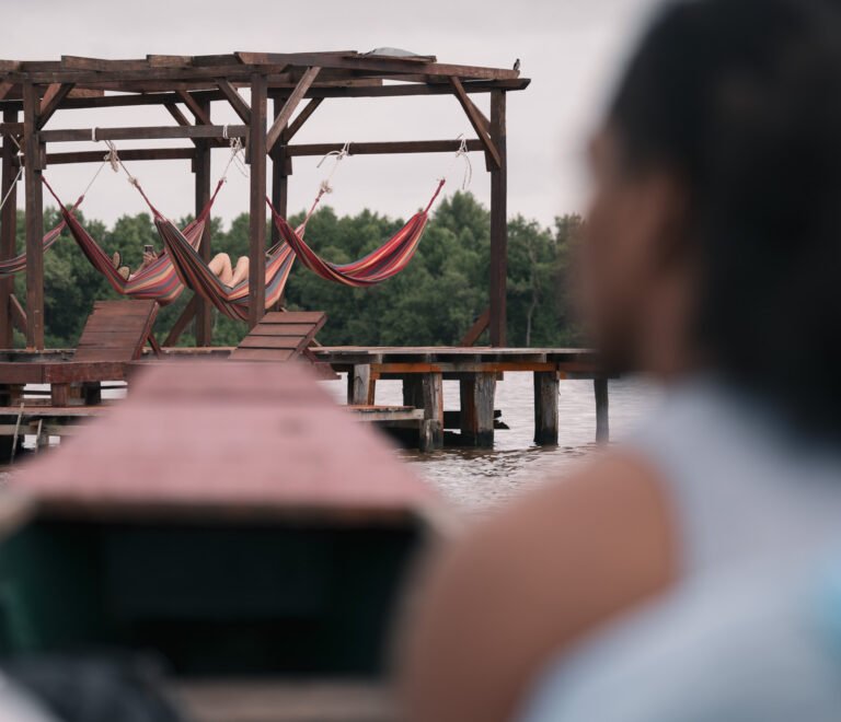 Guests relaxing in colorful hammocks on the riverside deck at Stephanie’s Lodge in Suriname