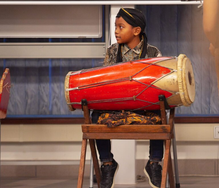 Young musician playing an Indonesian-style drum during a Javanese-Surinamese cultural performance