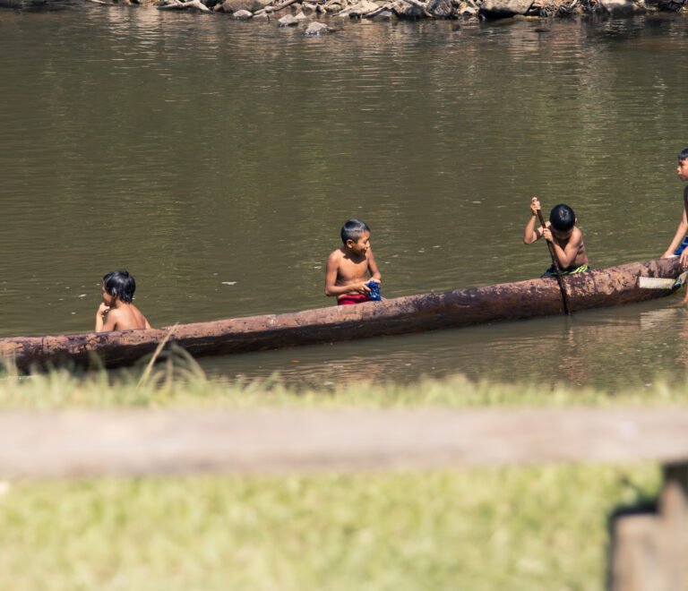 Children paddling a traditional wooden dugout canoe on a river in Suriname’s interior